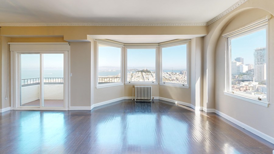 an empty living room with a view of the city and the ocean